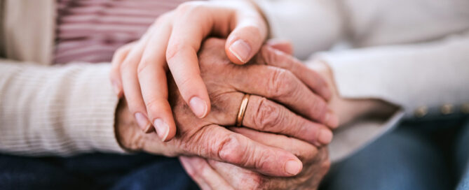Unrecognizable teenage girl with grandmother at home, holding hands. Family and generations concept. Close up.